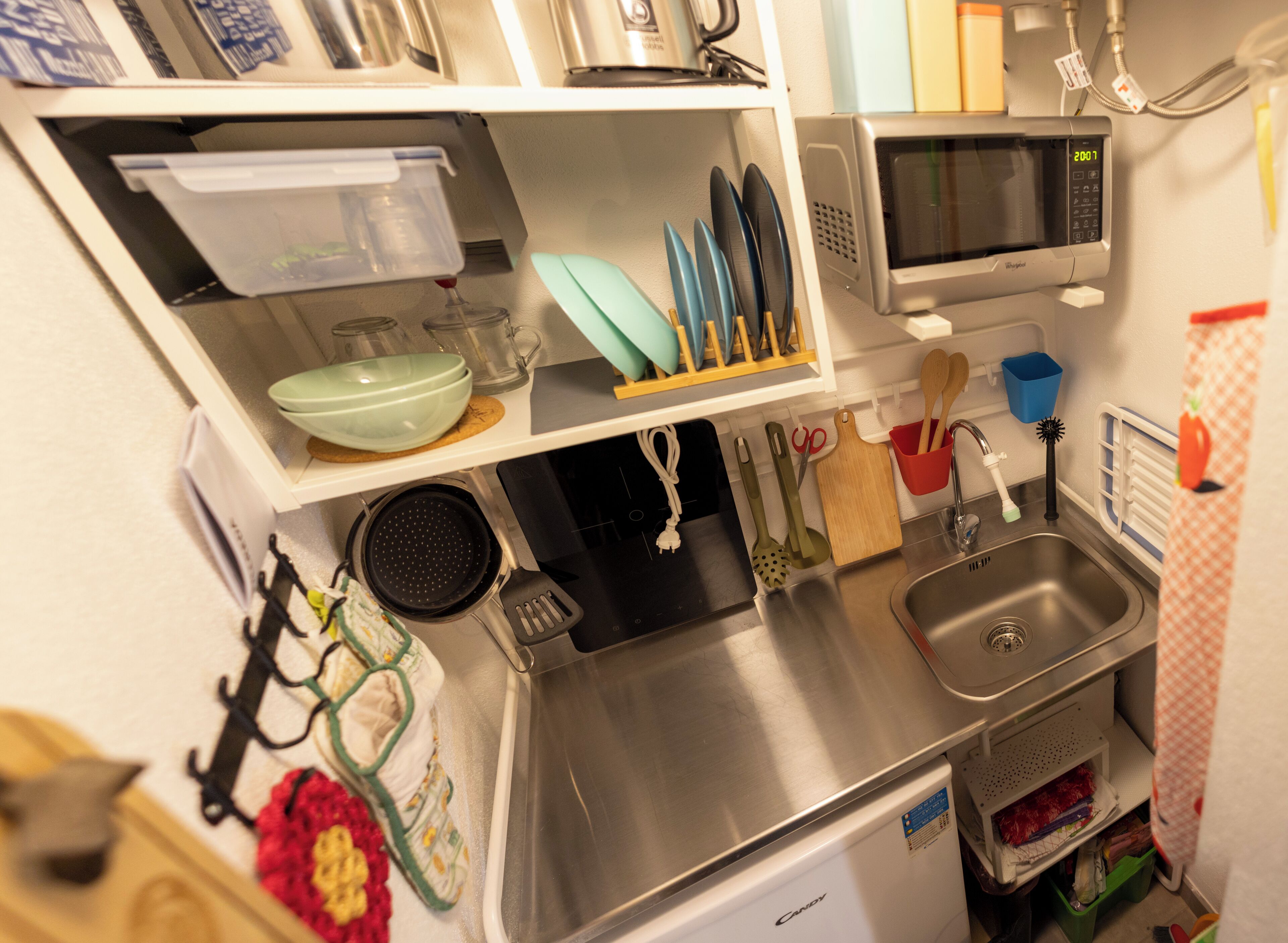 A compact kitchen with a microwave, sink, and various utensils.