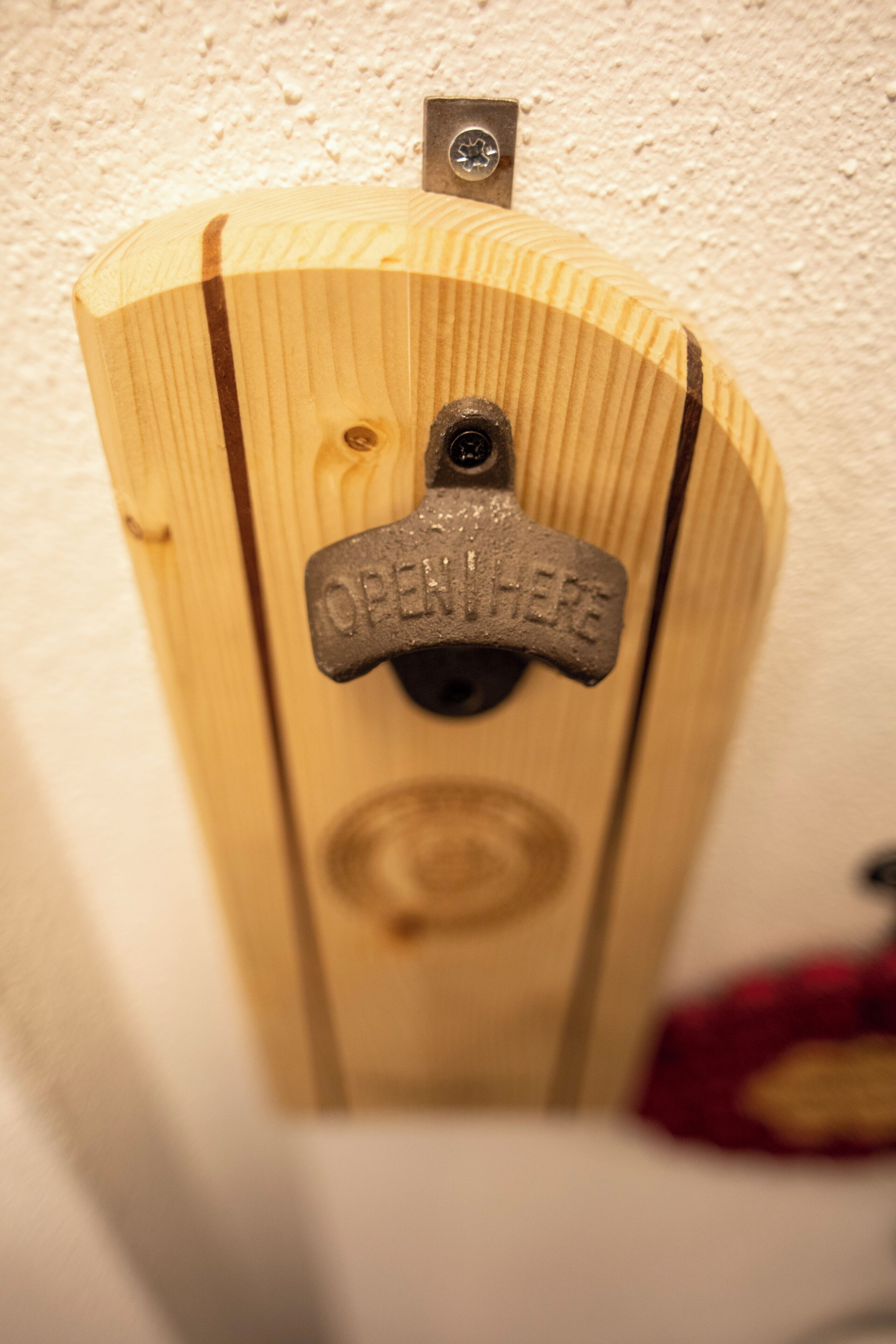 Een houten deur met een metalen handgreep en een bordje met de tekst 'OPEN HERE'.
