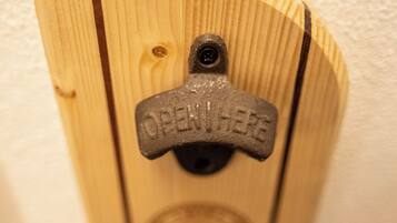 Een houten deur met een metalen handgreep en een bordje met de tekst 'OPEN HERE'.