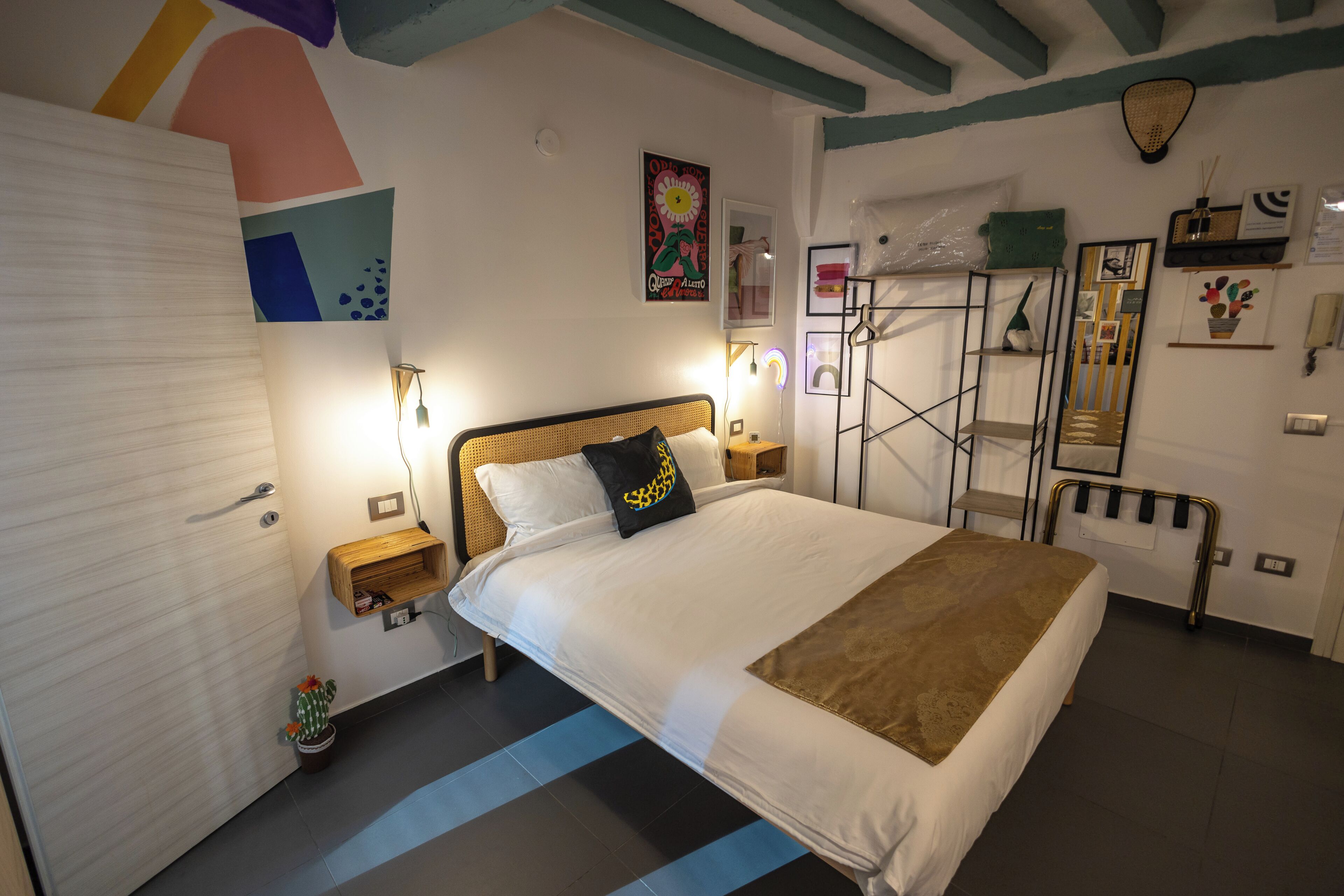 Une chambre bien rangée, avec un lit, des tables de chevet et une étagère fixée au mur.