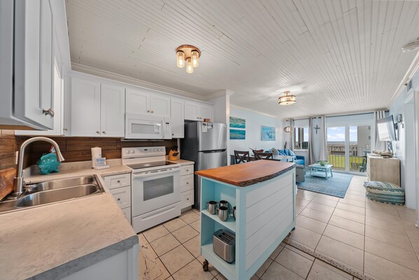 A modern kitchen with white cabinets, stainless steel appliances, and a wooden island. - GS Plantation East 3208 (Gulf Shores)