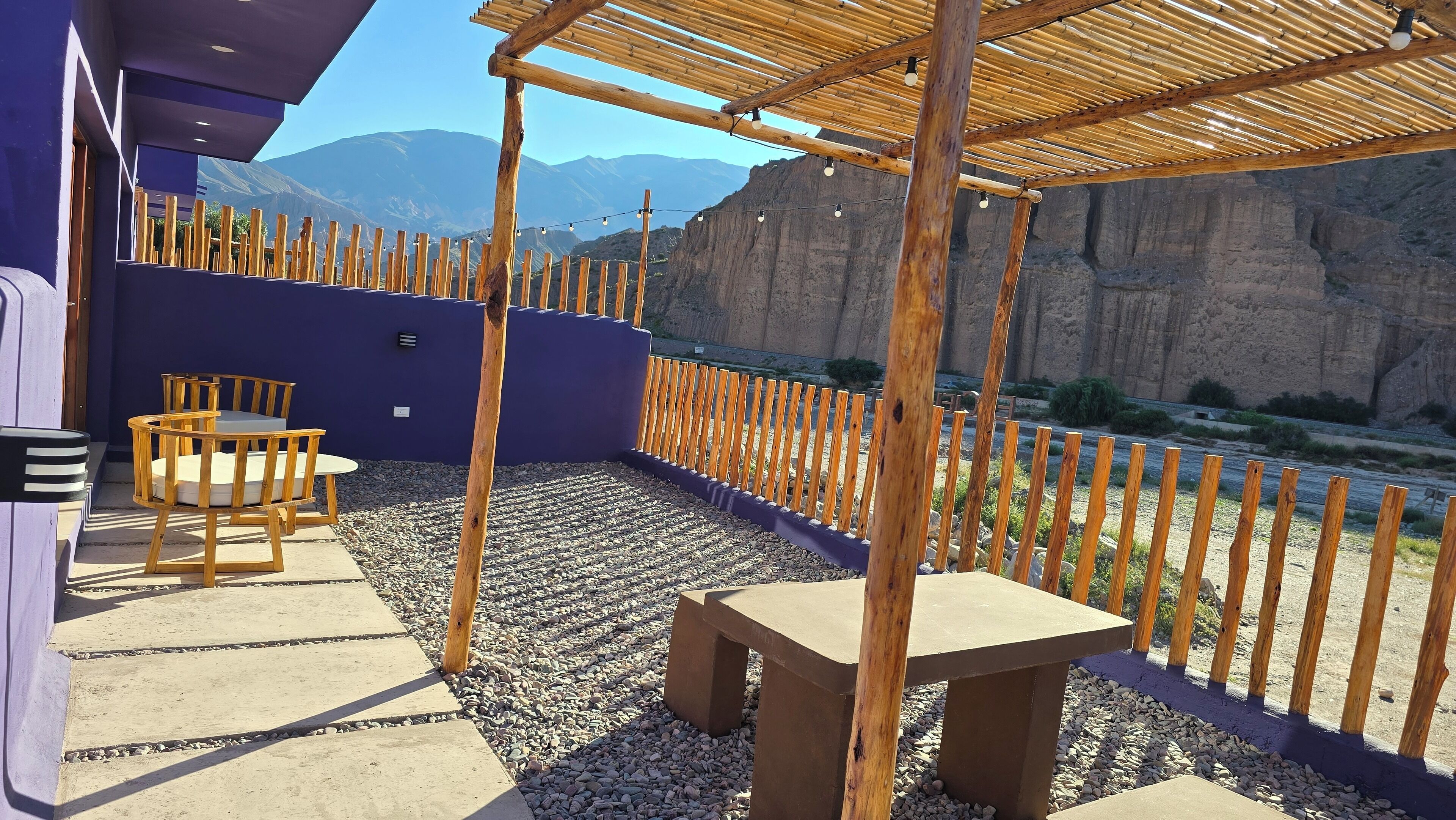 An outdoor patio with a wooden pergola, a table, and chairs.
