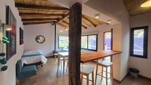 A room with a bed, a dining table, and a large window. - El cielo en Tilcara complejo turístico (Tilcara)