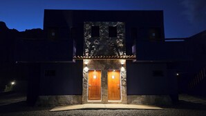 A modern building with a stone facade, two wooden doors, and a small balcony. - El cielo en Tilcara complejo turístico (Tilcara)