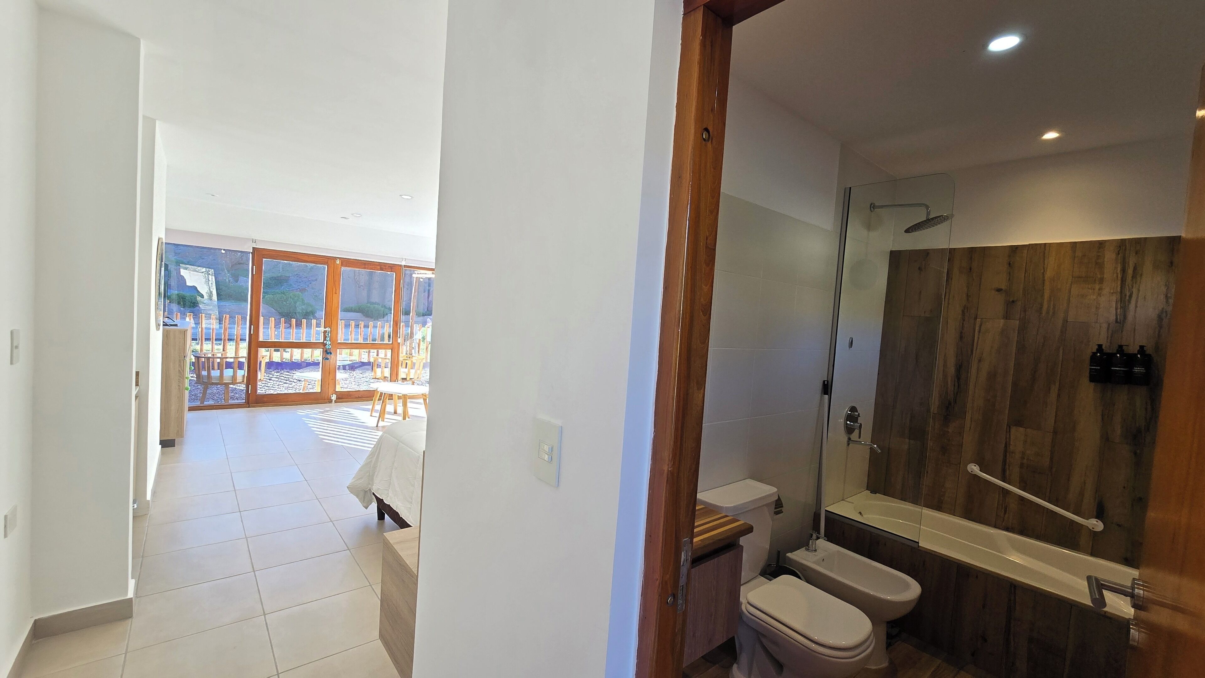 A modern bathroom with a wooden shower enclosure, a white toilet, and a bidet.