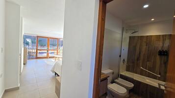 A modern bathroom with a wooden shower enclosure, a white toilet, and a bidet.