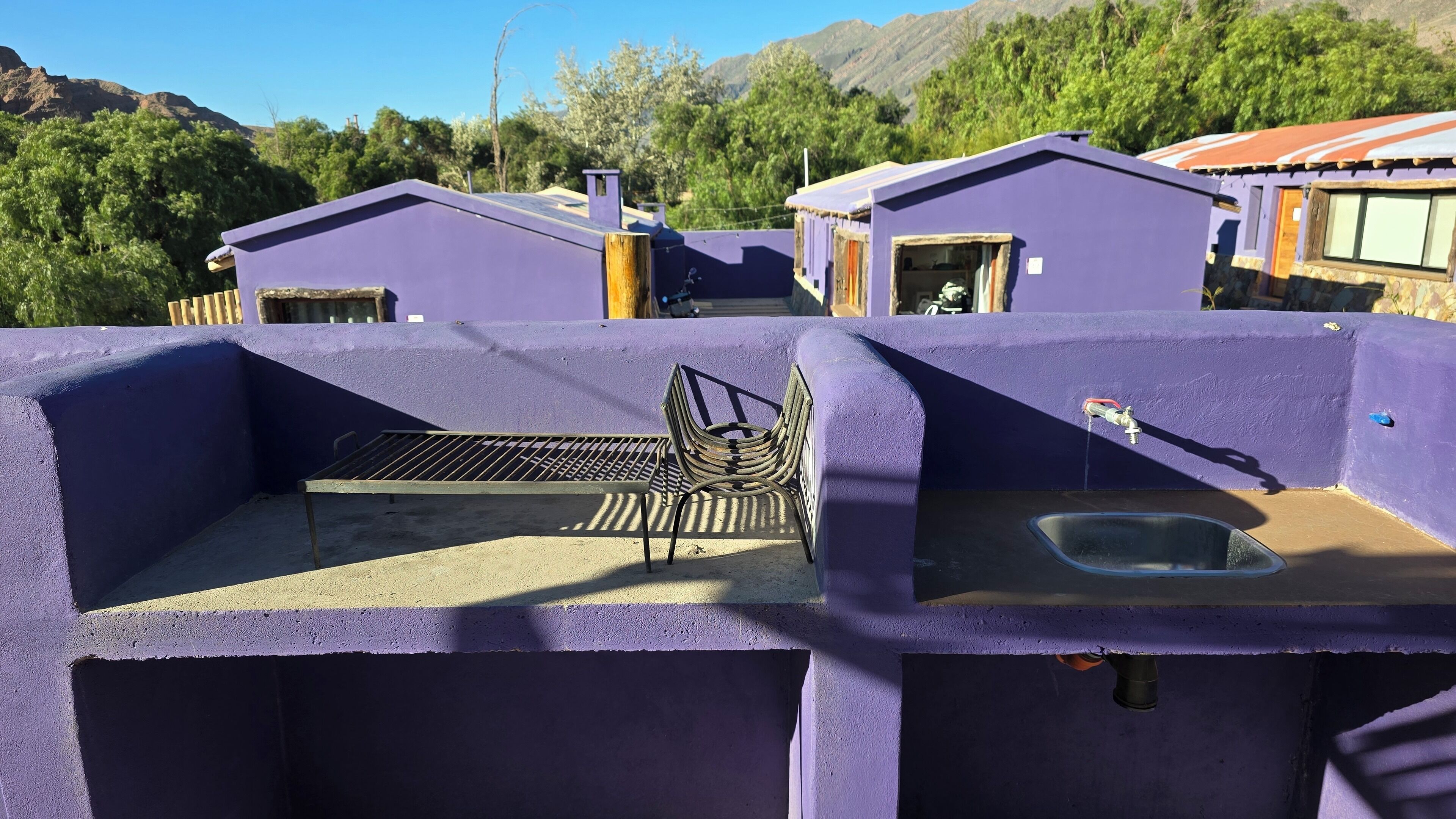 A purple building with a metal bench and a sink.