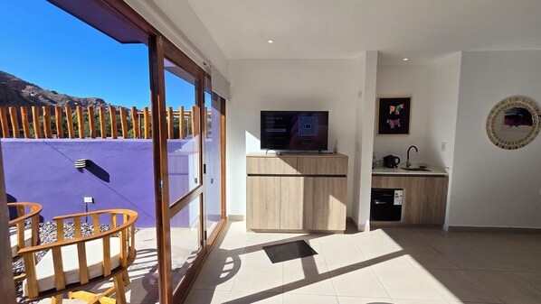 A modern kitchen with a built-in oven, a sink, and a flat-screen TV. There is a sliding glass door leading to an outdoor area with a wooden deck. - El cielo en Tilcara complejo turístico (Tilcara)