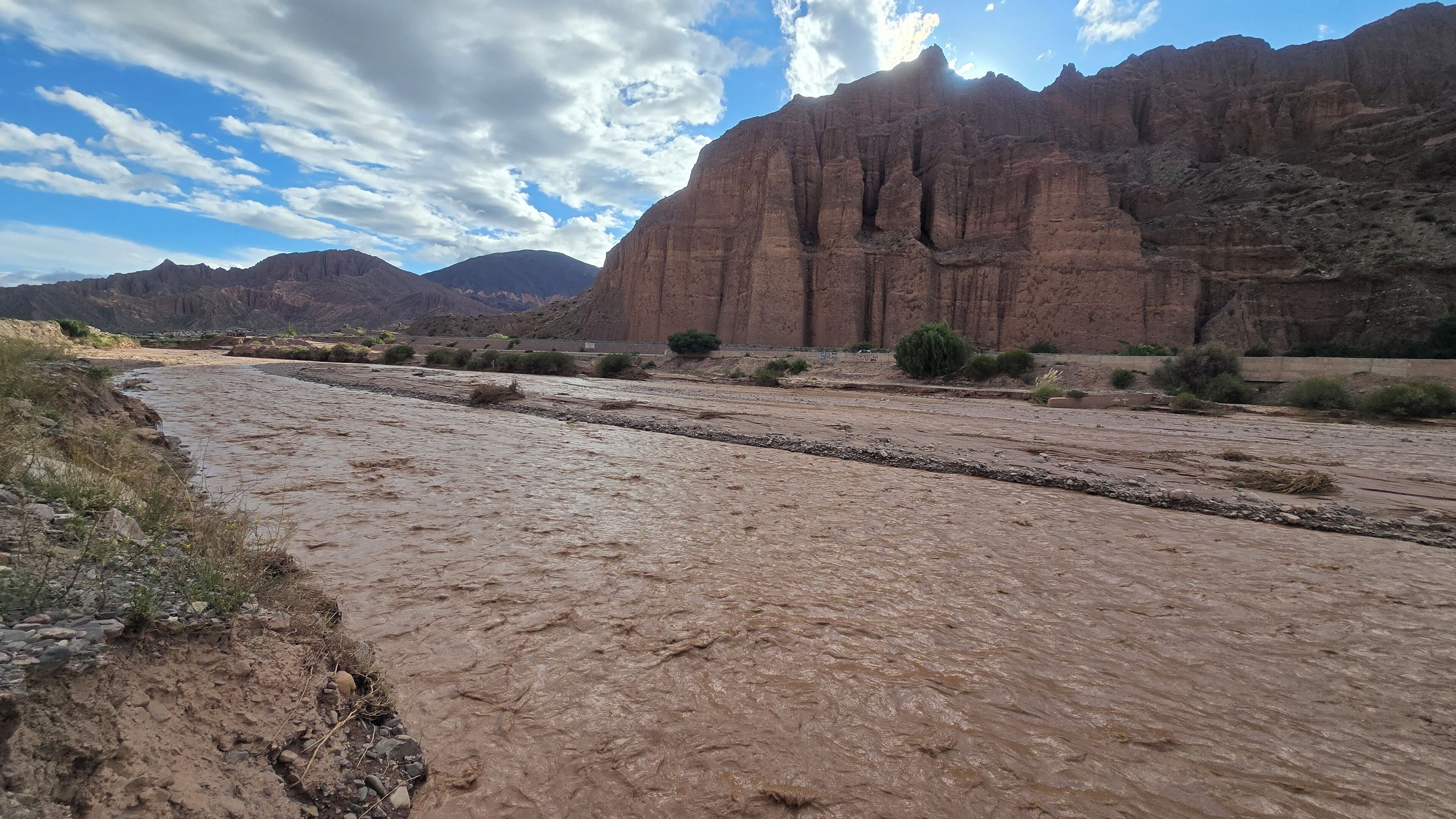 A riverbed with a rocky terrain and a large rock formation in the background.