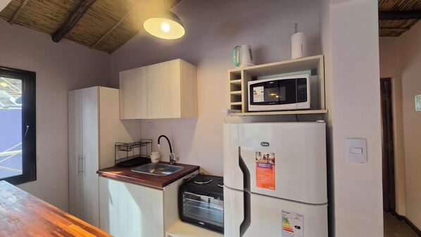 A compact kitchen with a sink, a microwave, and a refrigerator.