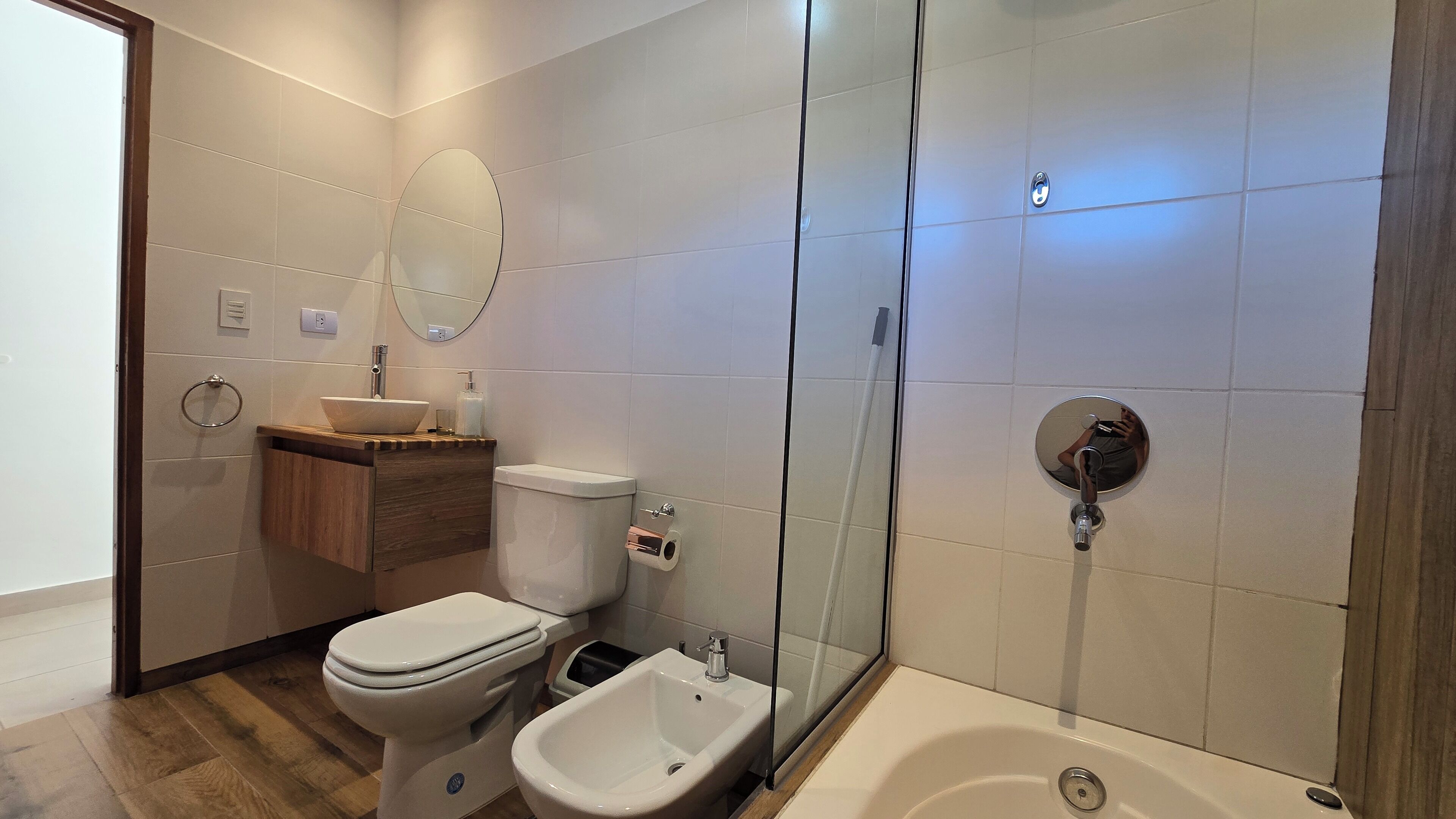 A bathroom with a toilet, bidet, sink, and a glass-enclosed shower area.
