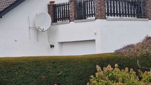 Uma casa branca com telhado preto, antena parabólica e chaminé de tijolos.