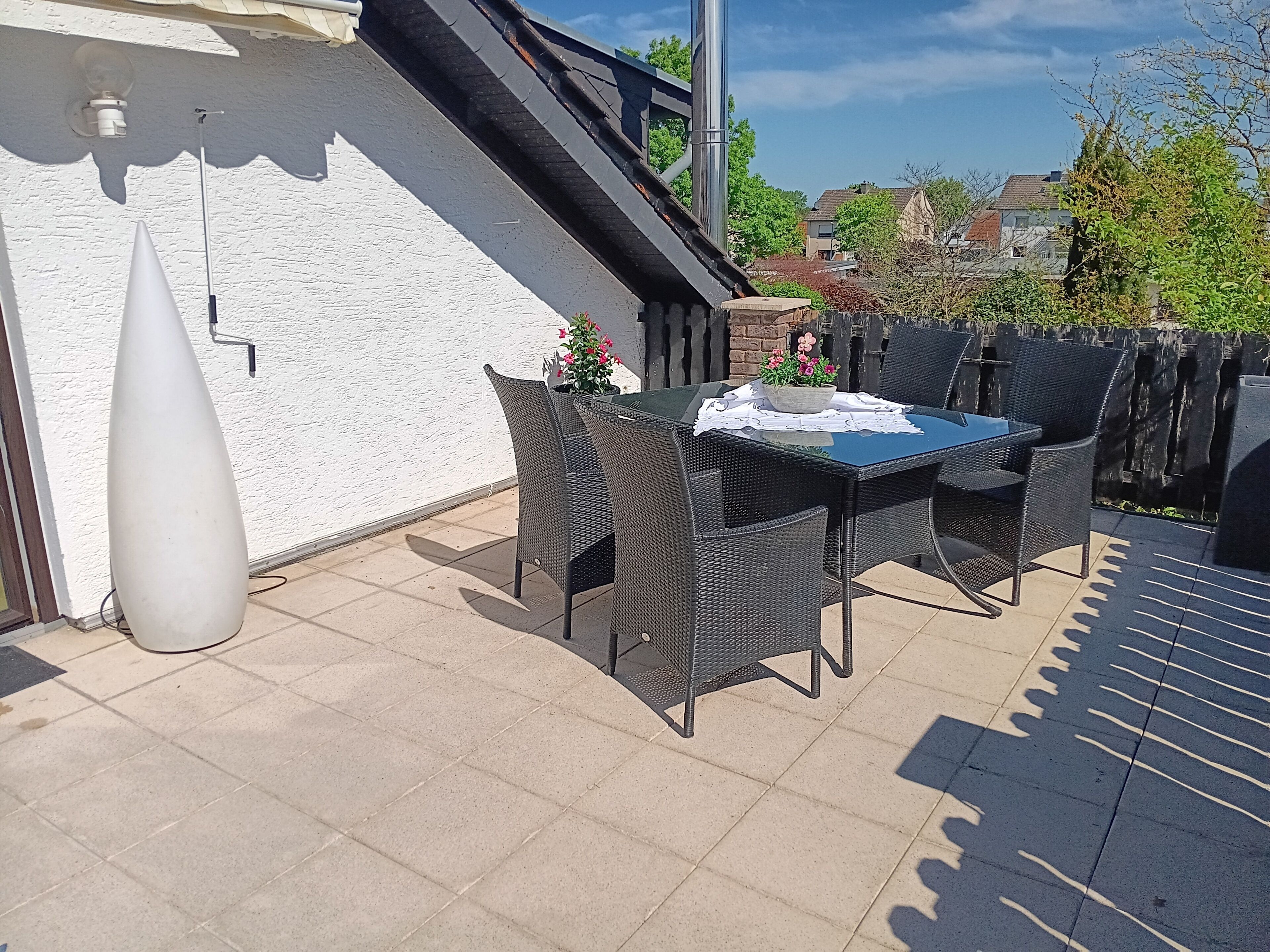 An outdoor patio with a table and chairs, a white wall, and a staircase.