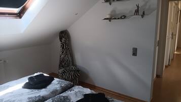Ein Schlafzimmer mit Oberlicht, einem zebra-gemusterten Sessel, einem Bett mit gemusterten Textilien und einem Flur mit einer Tür.