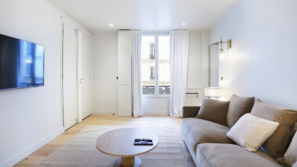 Una sala de estar moderna con un sofá, una mesa de centro y un televisor montado en la pared.