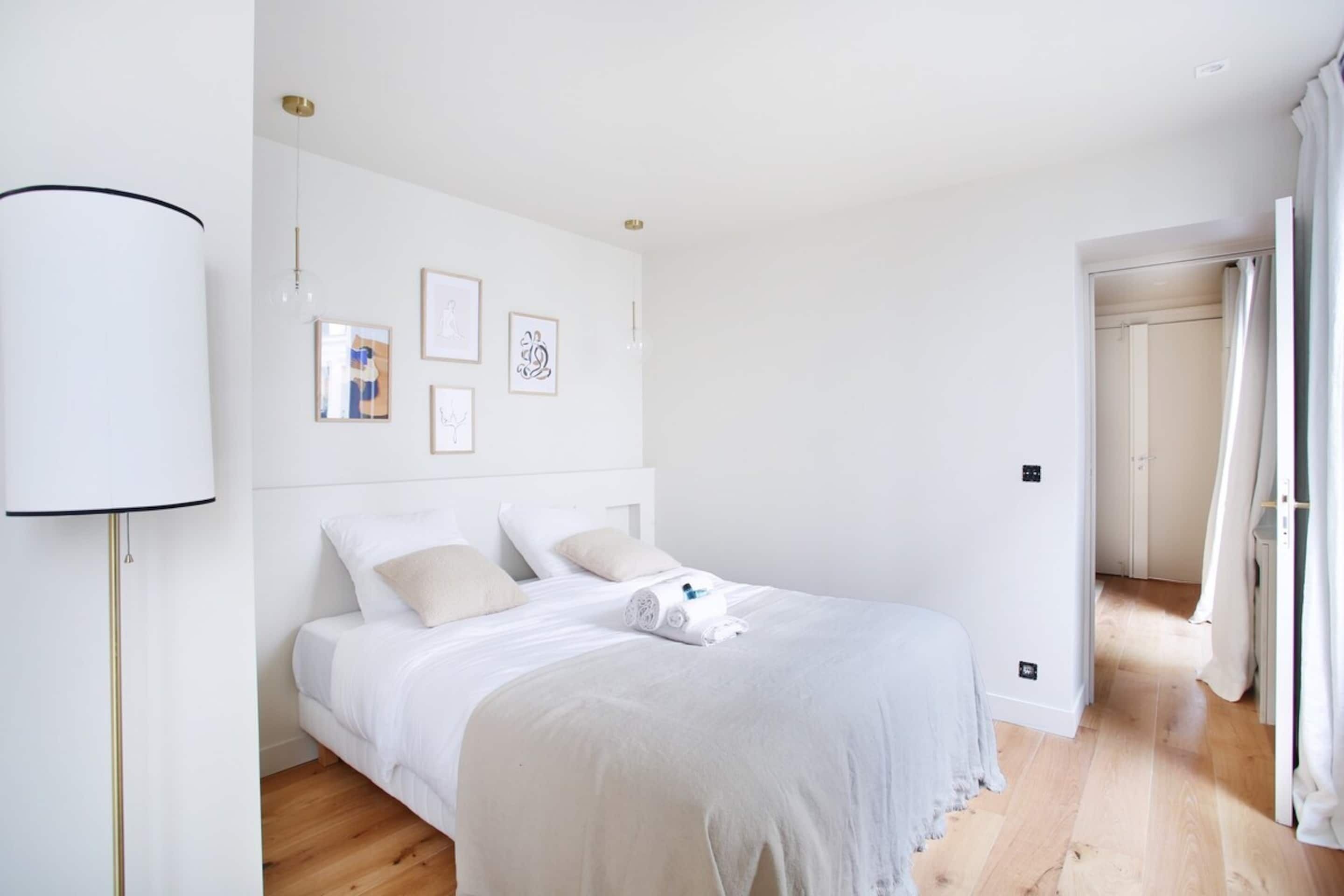 Ein Schlafzimmer mit einem Bett, einer Nachttischlampe und gerahmten Bildern an der Wand.