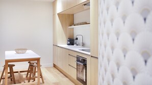 Una cocina moderna con armarios de madera, encimera blanca y horno empotrado.
