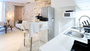 Cocina compacta con refrigerador blanco, microondas y pileta. Hay un comedor con mesa y sillas.