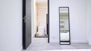 Habitación de hotel moderna con una cama grande, un espejo y vistas al baño.