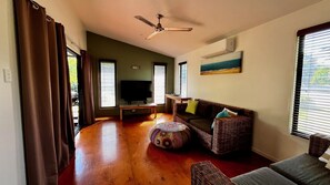 Relax in this spacious living room with a high ceiling, comfortable sofa set, and large windows.