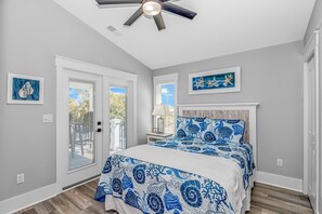 Quarto com cama, ventilador de teto e obras de arte nas paredes.