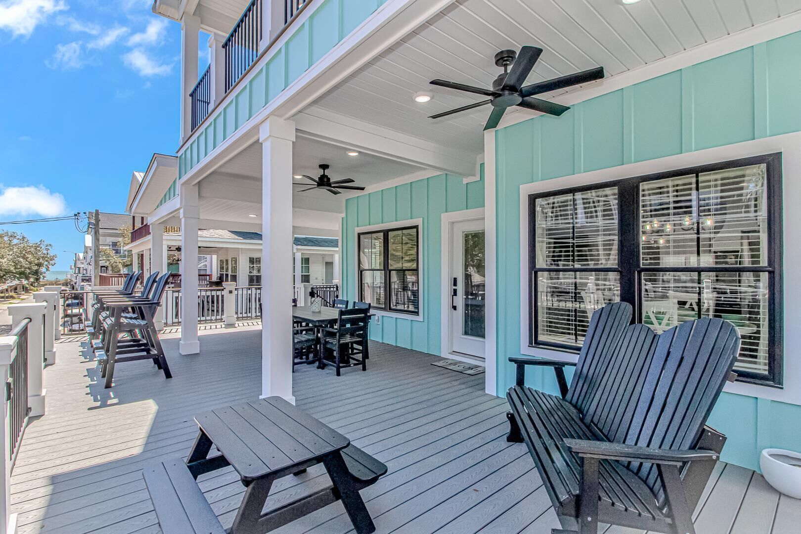 A covered outdoor deck with a table and chairs, a ceiling fan, and a view of the ocean.