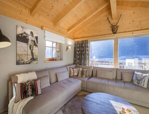 A cozy living room with a large sectional sofa, a round coffee table, and a wooden ceiling. - Family Ski Chalet With Views (Wald im Pinzgau)