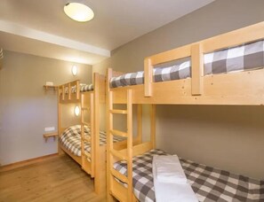 A bunk bed room with a wooden floor, a light fixture on the ceiling, and a checkered bedspread. - Family Ski Chalet With Views (Wald im Pinzgau)