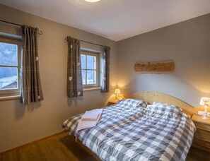 A bedroom with a bed, two bedside lamps, a window with curtains, and a wall-mounted headboard. - Family Ski Chalet With Views (Wald im Pinzgau)