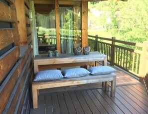 Una terraza de madera con un banco y dos macetas.