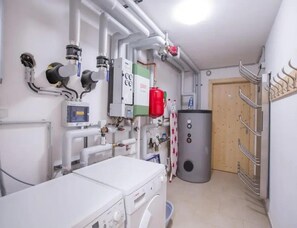 A laundry room with industrial equipment, a water heater, and a metal rack for hanging items. - Family Ski Chalet With Views (Wald im Pinzgau)