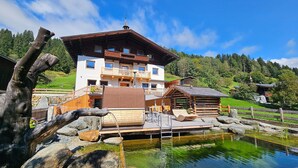 Ein Chalet mit Holzterrasse und einem kleinen Teich.