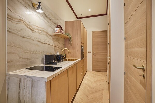 A modern kitchen with a marble backsplash, wooden cabinets, and a built-in oven. - Sublime Apartment With AC - Louvre Museum (Paris)