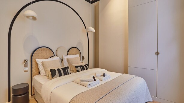 Una camera da letto moderna con una testiera sagomata, un ampio guardaroba e un comodino con una lampada.