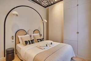 A modern bedroom with a curved headboard, a large wardrobe, and a bedside table with a lamp. - Sublime Apartment With AC - Louvre Museum (Paris)