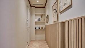 Un corridoio con pavimento a spina di pesce, rivestimento in legno a destra e scaffali con oggetti decorativi.