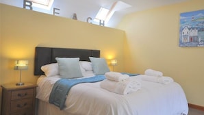 Une chambre à coucher avec un lit, deux tables de chevet, une tête de lit et un tableau au mur.