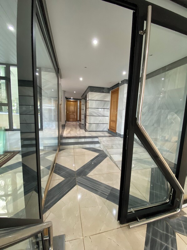 Un interior moderno con una puerta de cristal que da a un pasillo con suelo de estampado geométrico.