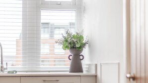 Eine Küche mit Fenster, Blumen in einer Vase und einem Esstisch.