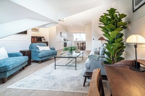 Ein modernes Wohnzimmer mit einer Couch, einem Couchtisch und einer großen Pflanze.