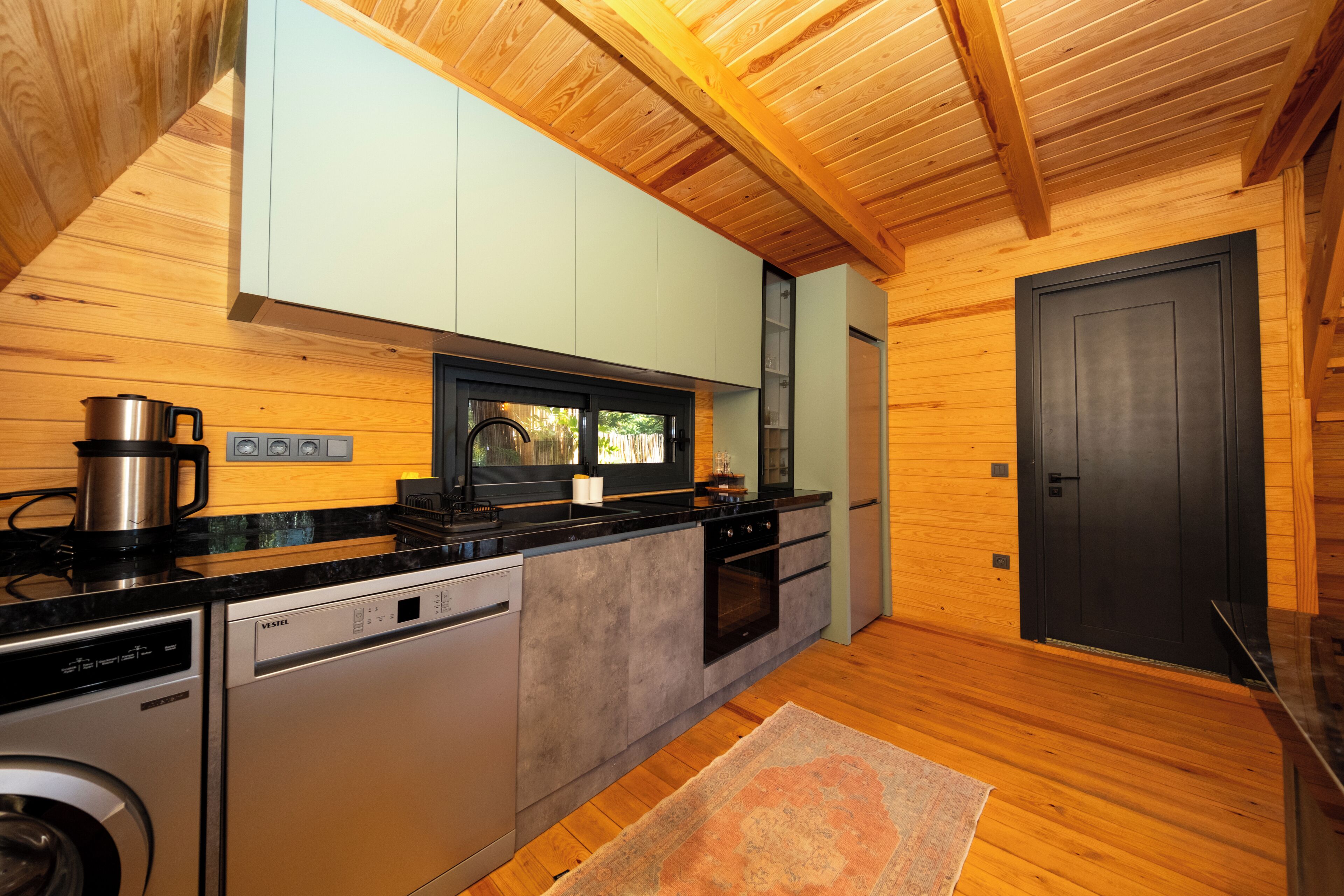 A compact kitchen with a dishwasher, oven, and a coffee maker.