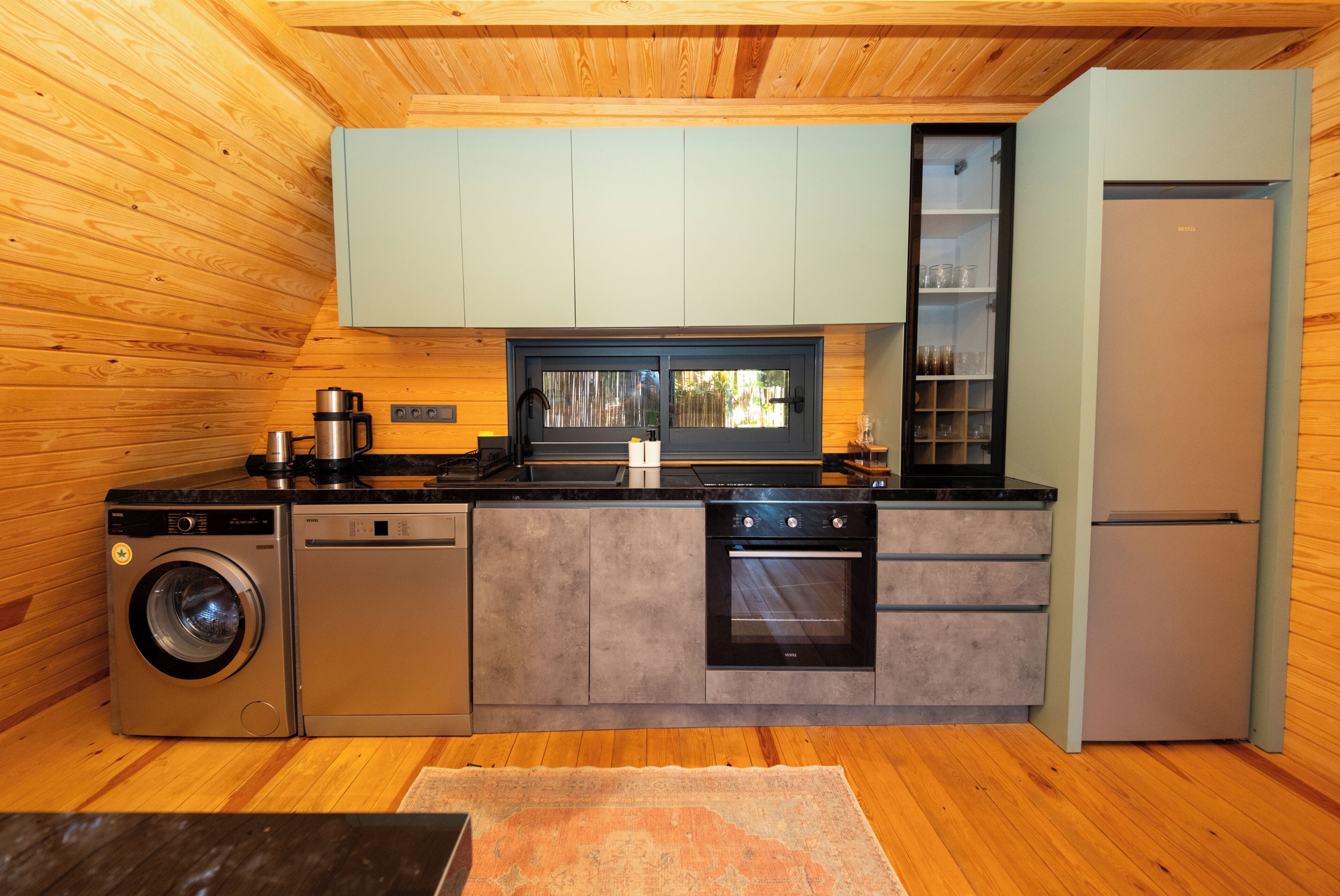 A compact kitchen with a washing machine, oven, and refrigerator.