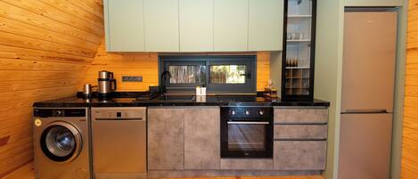 A compact kitchen with a washing machine, oven, and refrigerator.