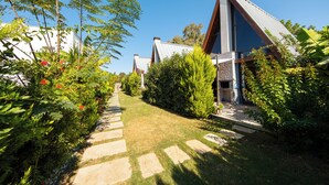 A pathway leading to a row of modern houses with a garden and greenery on either side. - BEGONVİL GÜMÜŞLÜK  (Bodrum)
