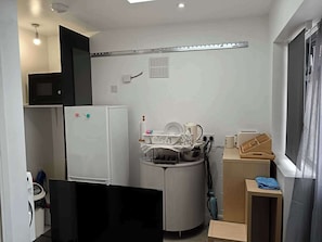 A compact kitchen with a microwave, refrigerator, and a small dining area with a table and chairs. - High Wycombe 1-bed Apt, Sleeps 3 & Private Parking (High Wycombe)