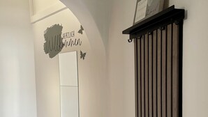 En gang med hvide vægge, en sort, lodret panel og et billede med et hjerte og tekst.