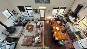 A spacious living area with a large wooden dining table, leather sofas, and a cozy fireplace. - Farmhouse Getaway - Firepit, Views & Stargazing (Castleton)