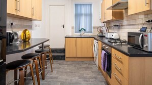 Een compacte keuken met houten kastjes, een inbouwoven, een magnetron en een spoelbak.