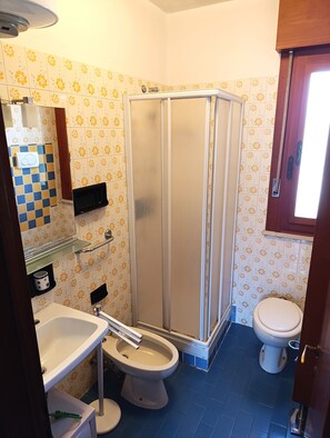 Ein Badezimmer mit Dusche, Toilette, Waschbecken und Spiegel.
