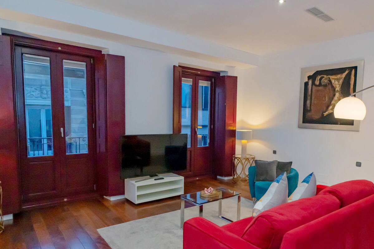 A living room with a red sofa, a TV, and a glass coffee table.